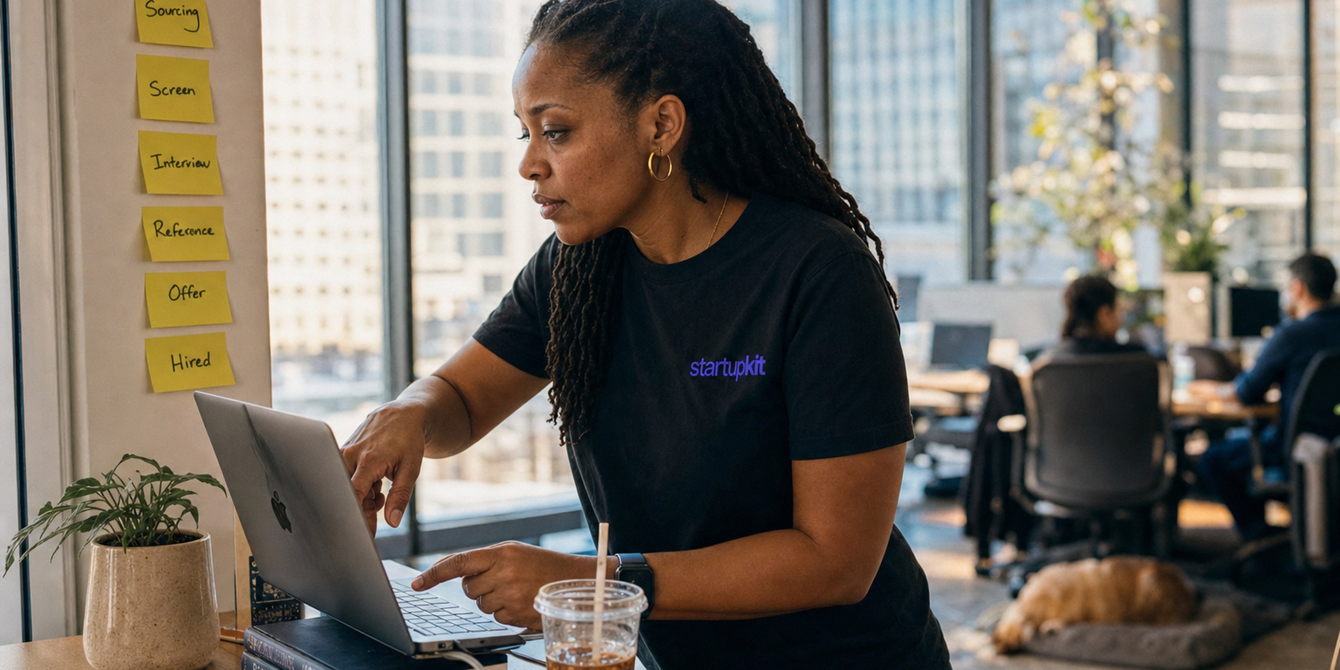 A head of talent at a sunlit co-working desk maps a hiring funnel on a laptop dashboard, tracing where candidates drop off between stages