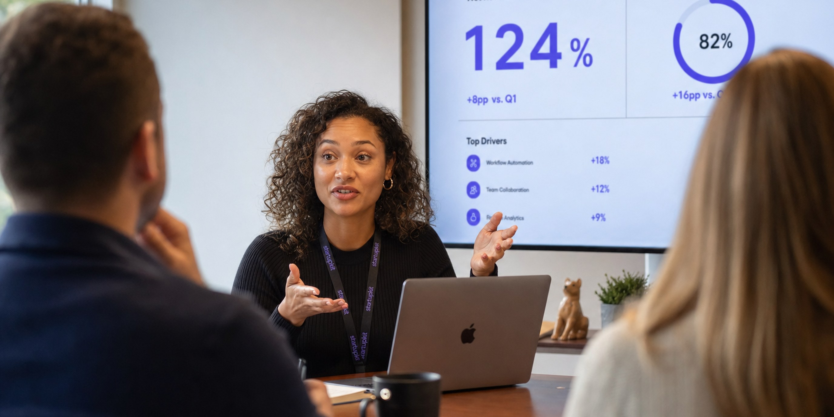 Customer Success Manager leading a quarterly business review with a client, net revenue retention and adoption metrics on the screen behind her