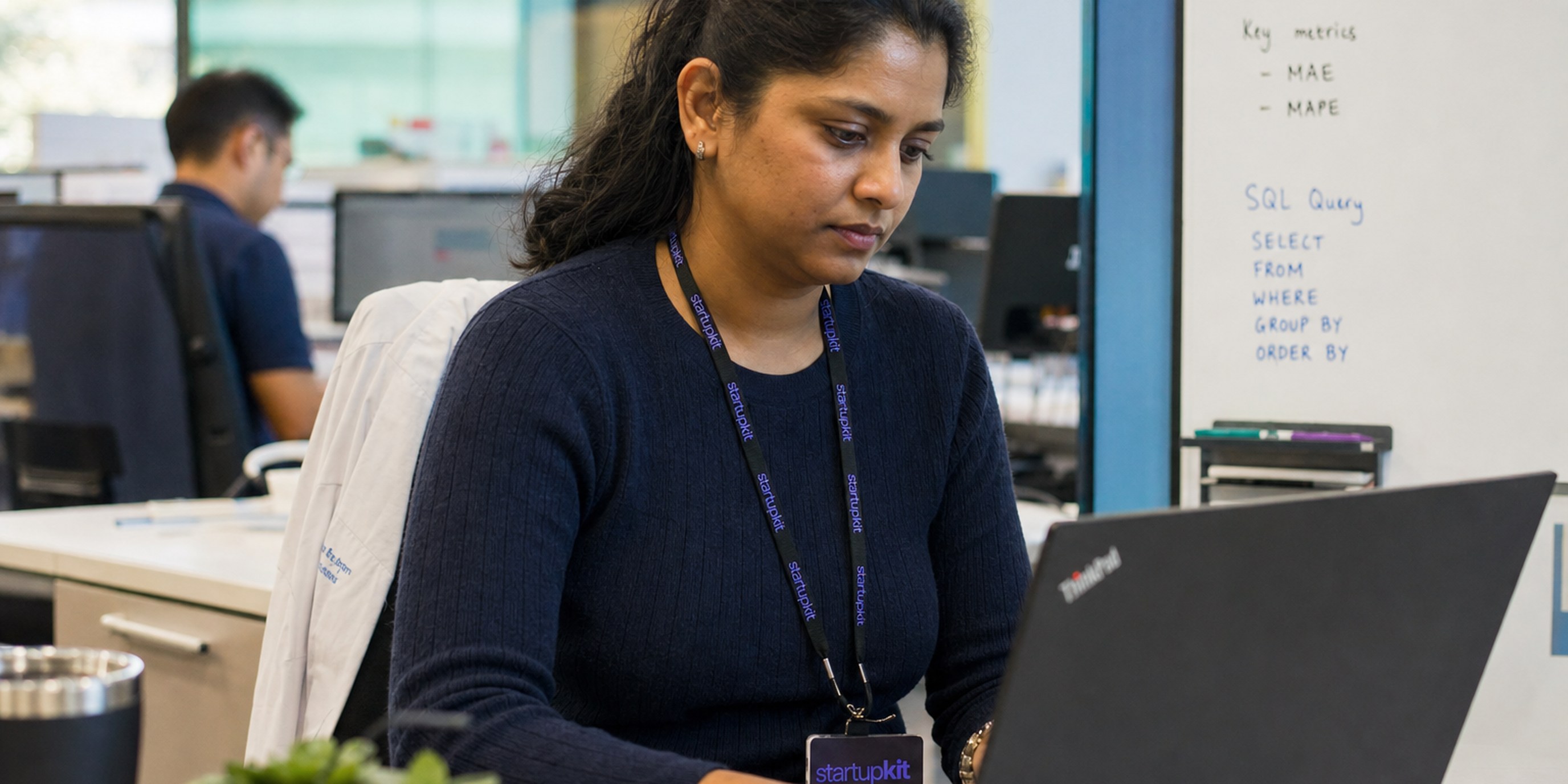 Data scientist reviewing a forecasting model and SQL query on a laptop in a hospital analytics office