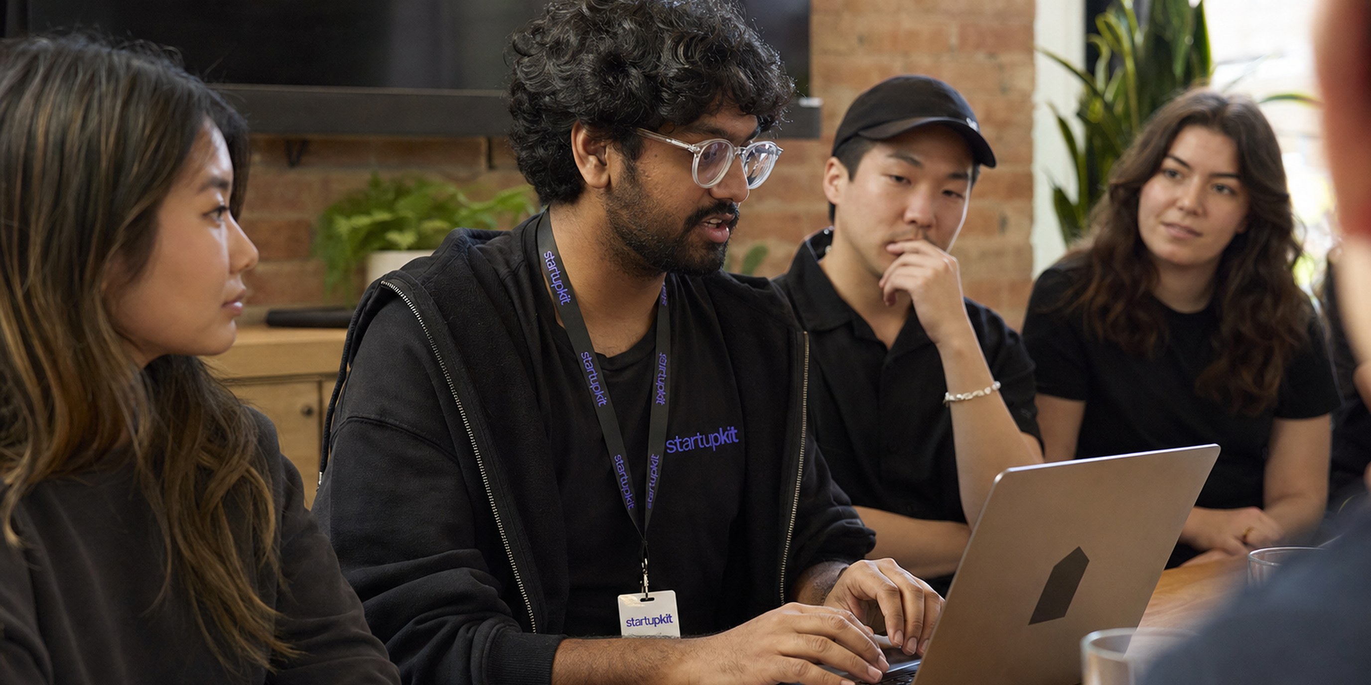 Developer Advocate live-coding an API demo on a laptop for a small group of developers during a startup hiring process