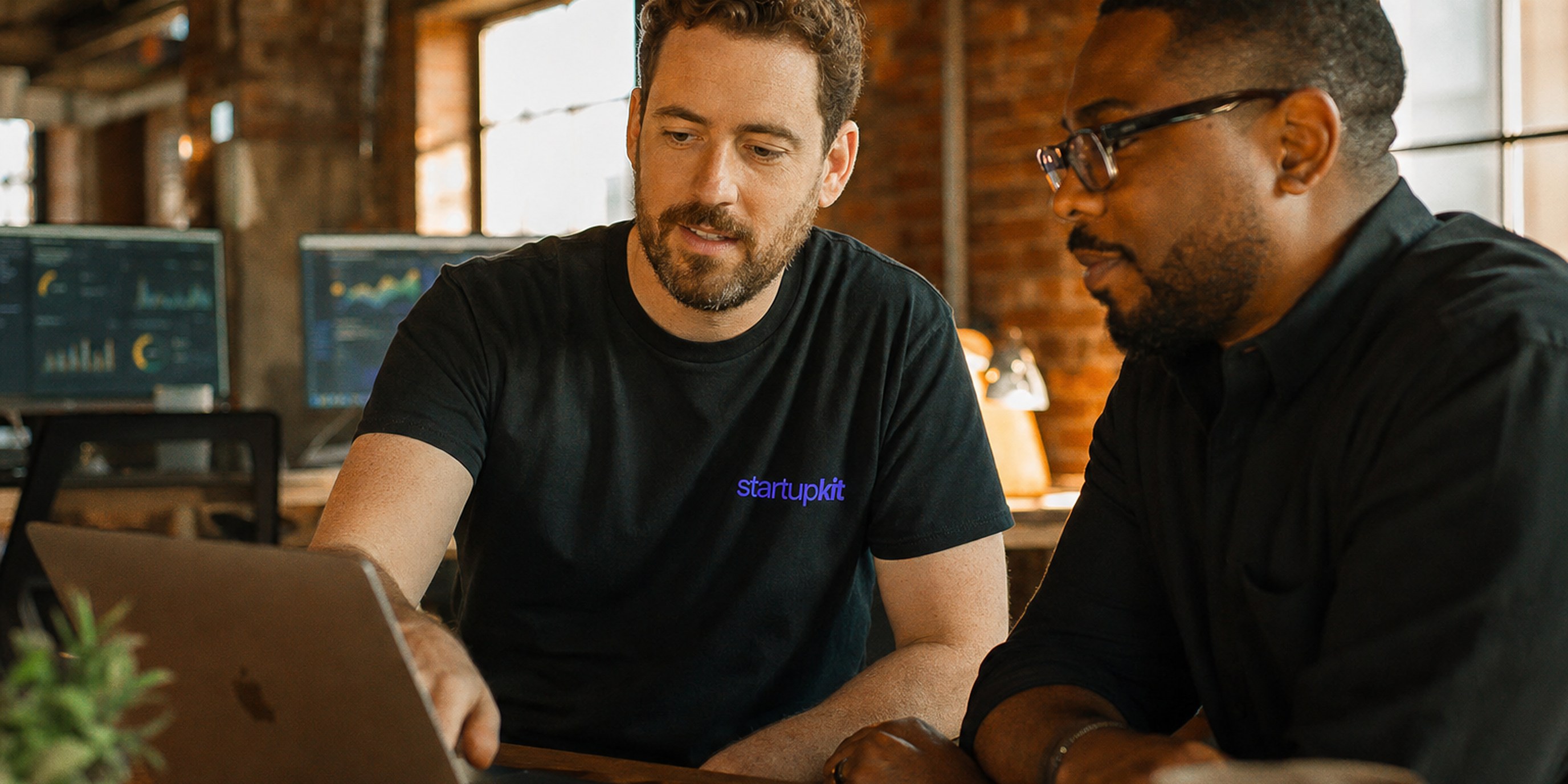 Forward deployed engineer in a startupkit tee working alongside a customer at a laptop