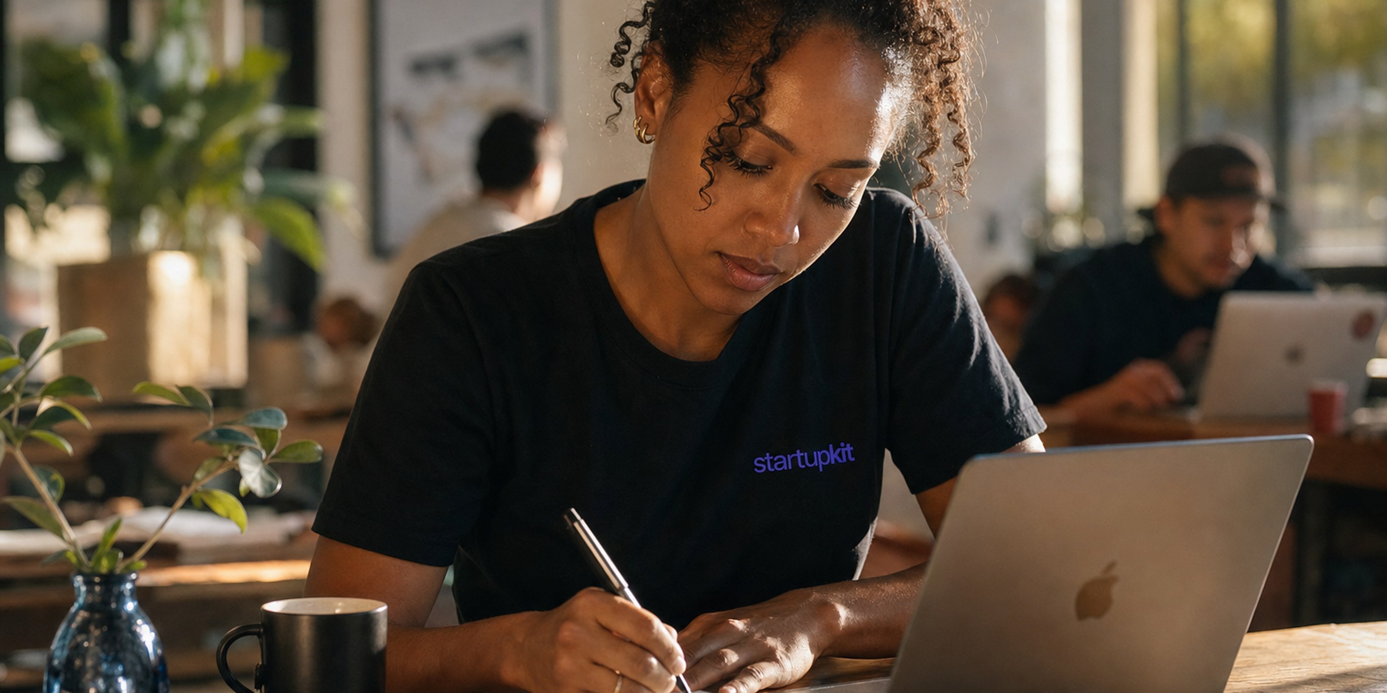 A startup founder reviewing a candidate's profile on her laptop before writing a single personalized outreach message at a sunlit co-working desk